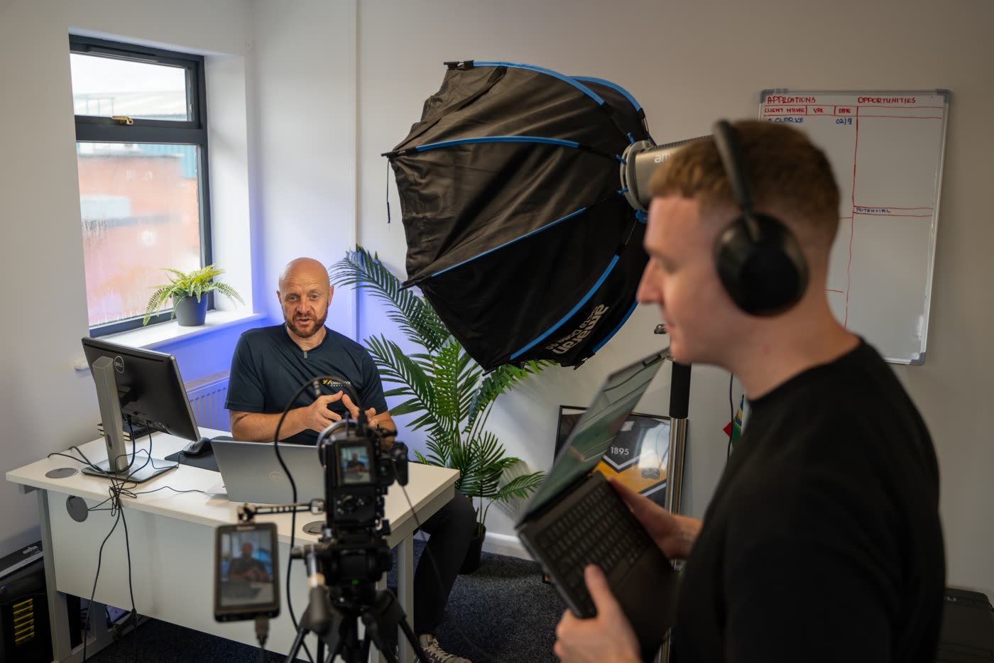 Louie with headphones and a script filming a mortgage broker in his office