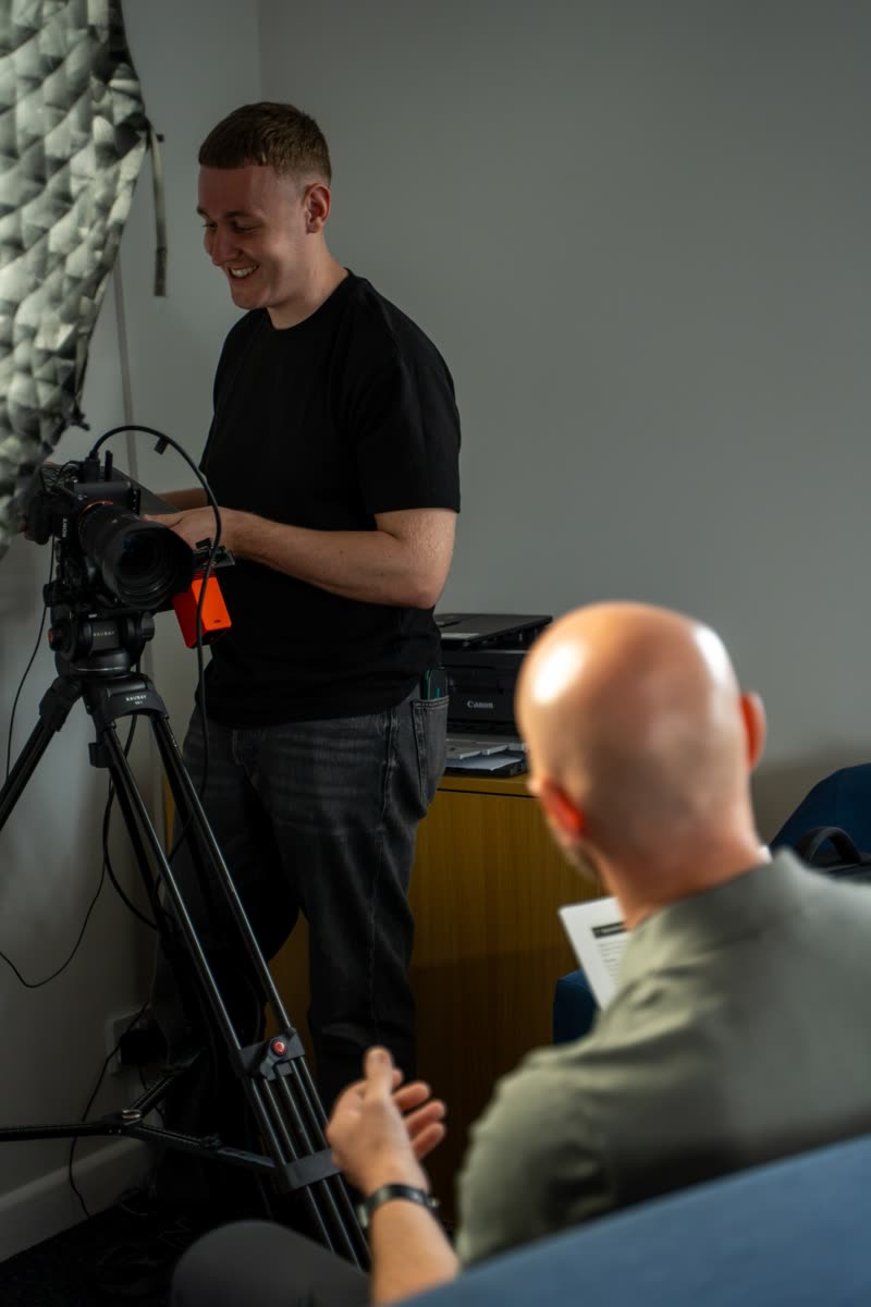 Louie setting up a camera on a tripod in an office